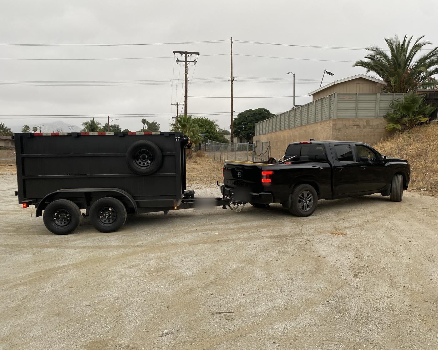 Black pickup towing a CDM dump trailer